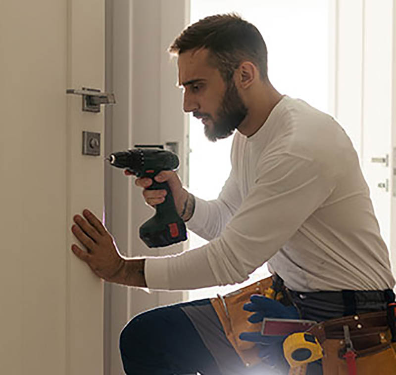 Portrait Young Male Carpenter Repairing Door Lock Servicio 24 horas: Siempre listos para ayudarte